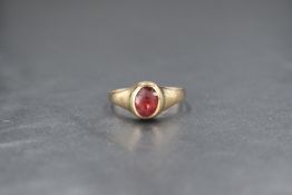 A yellow metal presumed gold red paste signet ring, the oval cut red paste set in a bezel setting,