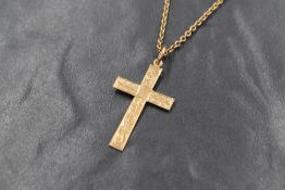 A yellow metal cross pendant having engraved scroll decoration on a 16' yellow metal chain, both
