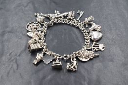 A white metal charm bracelet having twenty one charms bagpipes, leek etc, approximately 69.5g