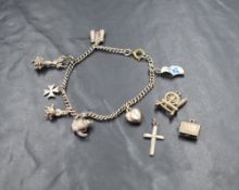 A white metal charm bracelet, having seven charms with an additional three being loose, including an