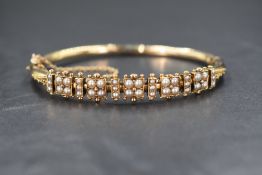 A yellow metal presumed gold seed pearl set hinged bangle, the five decorative pearl quads