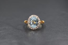 An 18ct gold aquamarine and diamond set cluster ring, the central oval cut aquamarine measuring