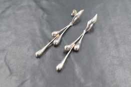 A pair of silver teardrop motif drop earrings, the wave motif top with an articulated teardrop trio,