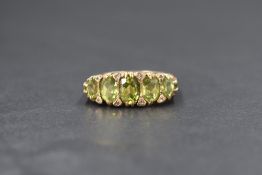 A 9ct gold peridot five stone set ring, the graduated oval cut peridots, measuring between