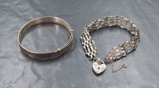 A silver four bar gate bracelet, having a silver heart padlock and broken safety chain, along with a