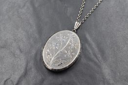 A large oval silver locket having floral decoration and brushed finish, on a 22' silver chain,