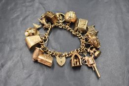 A 9ct gold curb link charm bracelet, having a padlock clasp and fifteen large charms including