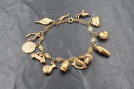 A 9ct gold fancy link bracelet having thirteen 9ct gold and yellow metal charms including an