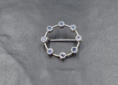 A white metal sapphire set brooch, the eight round cut sapphires in an open circular setting, 1.8g