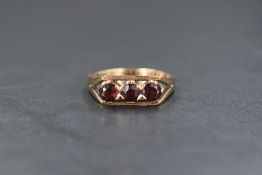 A 9ct gold garnet set trilogy ring, having a claw set mount in a box style setting with split