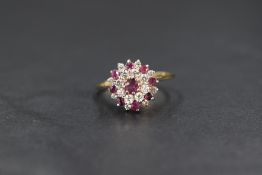 A yellow metal presumed gold ruby and cubic zirconia cluster ring, the central round cut ruby with