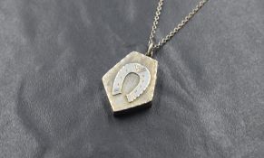 A Victorian silver locket of pentagon form bearing horse shoe motif to front, on a white metal