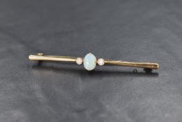 A yellow metal bar brooch stamped 9ct/plat having a central opal cabochon flanked by two small