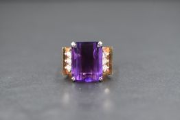 A modern yellow metal amethyst and diamond set ring, the emerald cut amethyst measuring