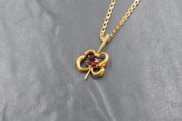 A 9ct gold pendant having central red paste stone in a floral style mount on a 9ct gold fancy link