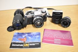 An Olympus OM20 camera with OM System Zuiko Auto S 1:1,8 50mm, an OM System Zuiko Auto 1:4,5 70-