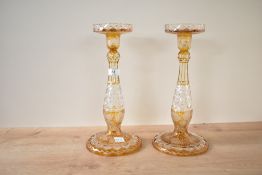 An attractive pair of Bohemian style cut crystal candlesticks, decorated with fruit and foliage on a