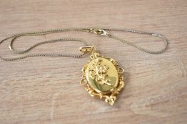 A yellow metal ornate locket having a decorative pierced scroll setting with embossed flowers to the