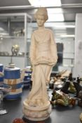 A cast composition figurine depicting a female holding a long basket flowers on marble base,
