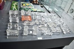 A collection of early 20th century clear cut crystal knife rests in various shapes and sizes,