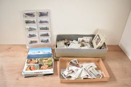 A box containing various vintage cigarette cards and post cards, subjects include railwayana and