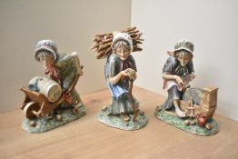 A group of three continental porcelain figurines depicting three old ladies, one on a grind stone,