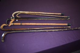 An assortment of seven sticks of varying lengths from 93cm to 79cm long including a silver topped