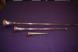 Three copper and brass hunting or post horns varying sizes 22cm to 104cm