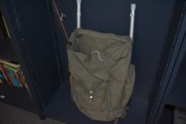 A green canvas frame rucksack containing five leather riding crops