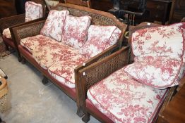 An early 20th Century lounge suite having oak frame and bergere canework sides and backs , with