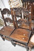 A pair of period oak dining chairs having carved backs in the Vernacular style having carved backs