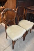 A pair of Victorian mahogany salon chairs having carved balloon/rail backs and later green dralon