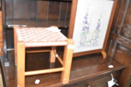An oak framed firescreen having embroidered panel and a traditional strung low stool