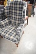 A traditional wing back armchair having modern check upholstery