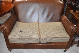 A modern tetrad leather two seater settee, with tweed style loose cushions (damage to castor)