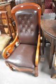 A Victorian mahogany framed easy chair having scroll arms and turned legs with brown leather