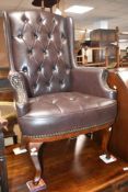 A modern brown leather button back armchair