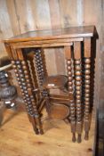 An early 20th Century oak nest of tables having bobbin turned frame and shelved undertier to smaller