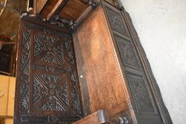 A late 19th or early 20th Century oak monks bench having carved panel decoration , width approx.