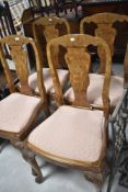 A set of four early to mid 20th Century walnut dining chairs having vase backs and drop in seats