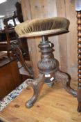 A 19th Century piano stool having swivel seat and heavily carved frame