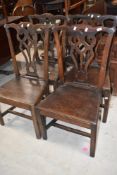 A set of four Georgian oak dining chairs having slat backs and solid seats
