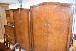 An early 20th Century walnut bedroom suite comprising two wardrobes, dressing table, set of five