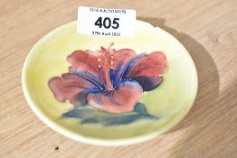 A Moorcroft Pottery small footed bowl having yellow backgroung in the Hibiscus pattern. AF chip to