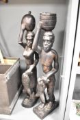 A pair of carved hard wood African tribal sculptures each carrying fish and vessels, h69cm