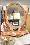 An early 20th century walnut swing dressing mirror of oval form, having carved floral decoration and