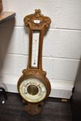 An early 20th century oak barometer having temperature gauge and carved floral decoration, h81cm