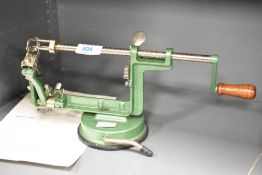 A vintage table top hand cranked apple peeling machine, having wooden handle and green crack