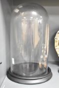A modern clear glass display dome and circular moulded stand 35cm
