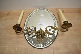 A vintage oval wall mirror attached with two gilt metal candle sconces, h40cm